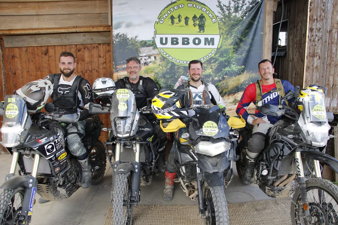Vier Fahrer mit ihren Reiseenduros vor dem UBBOM-Banner.